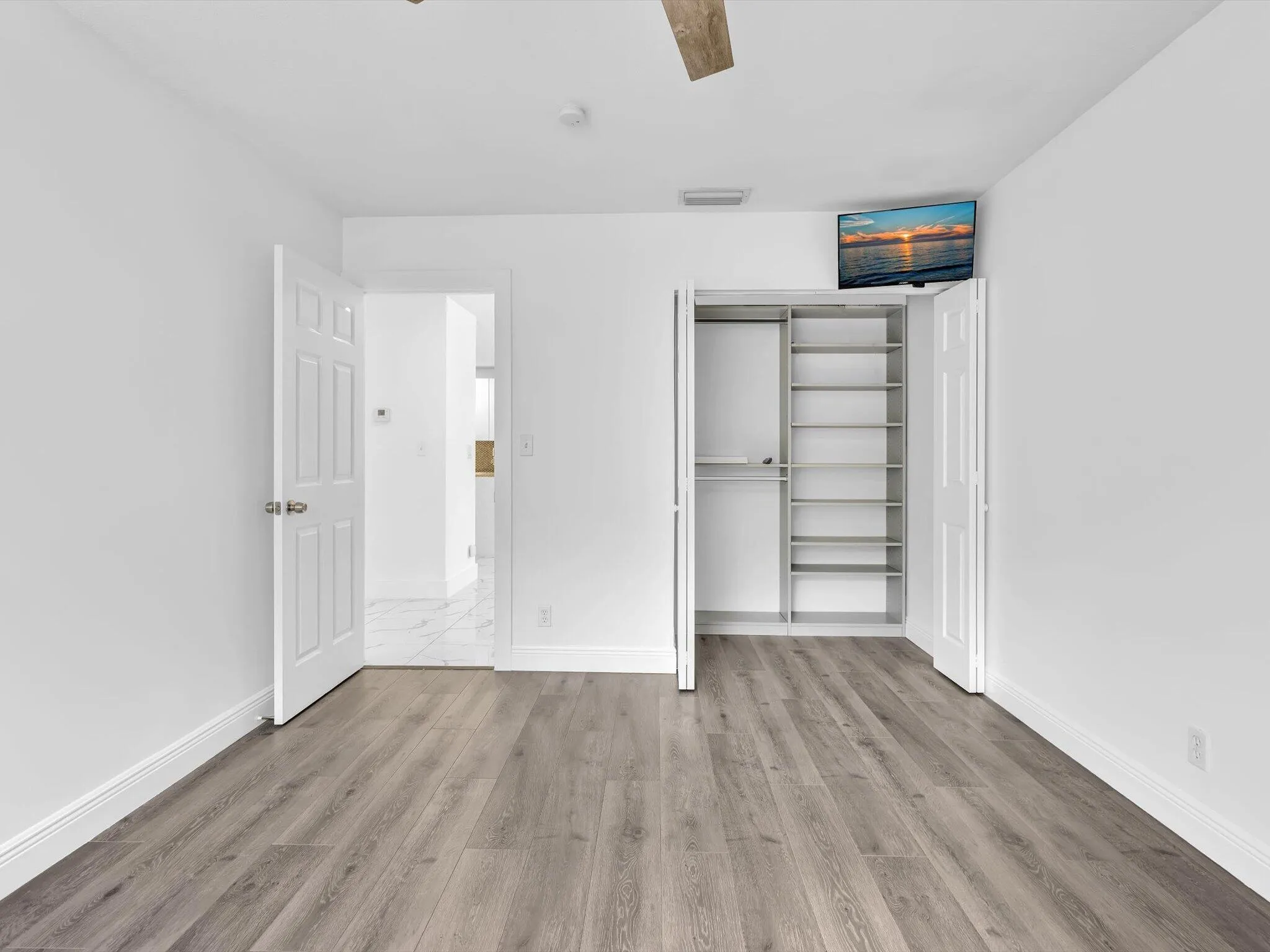 Wood-finish flooring with white baseboards and neutral wall paint