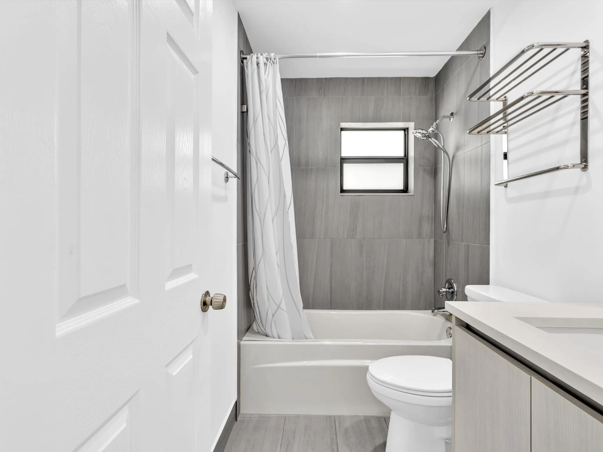 Recessed window in shower, full-sized bathtub, floor-to-ceiling shower tile, single vanity with integrated sink, and wood-finish flooring