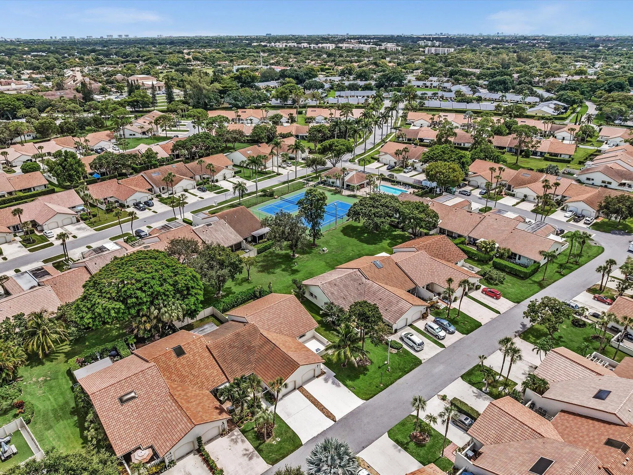 Community showcasing residential properties with tile roofs, mature landscaping, and private driveways