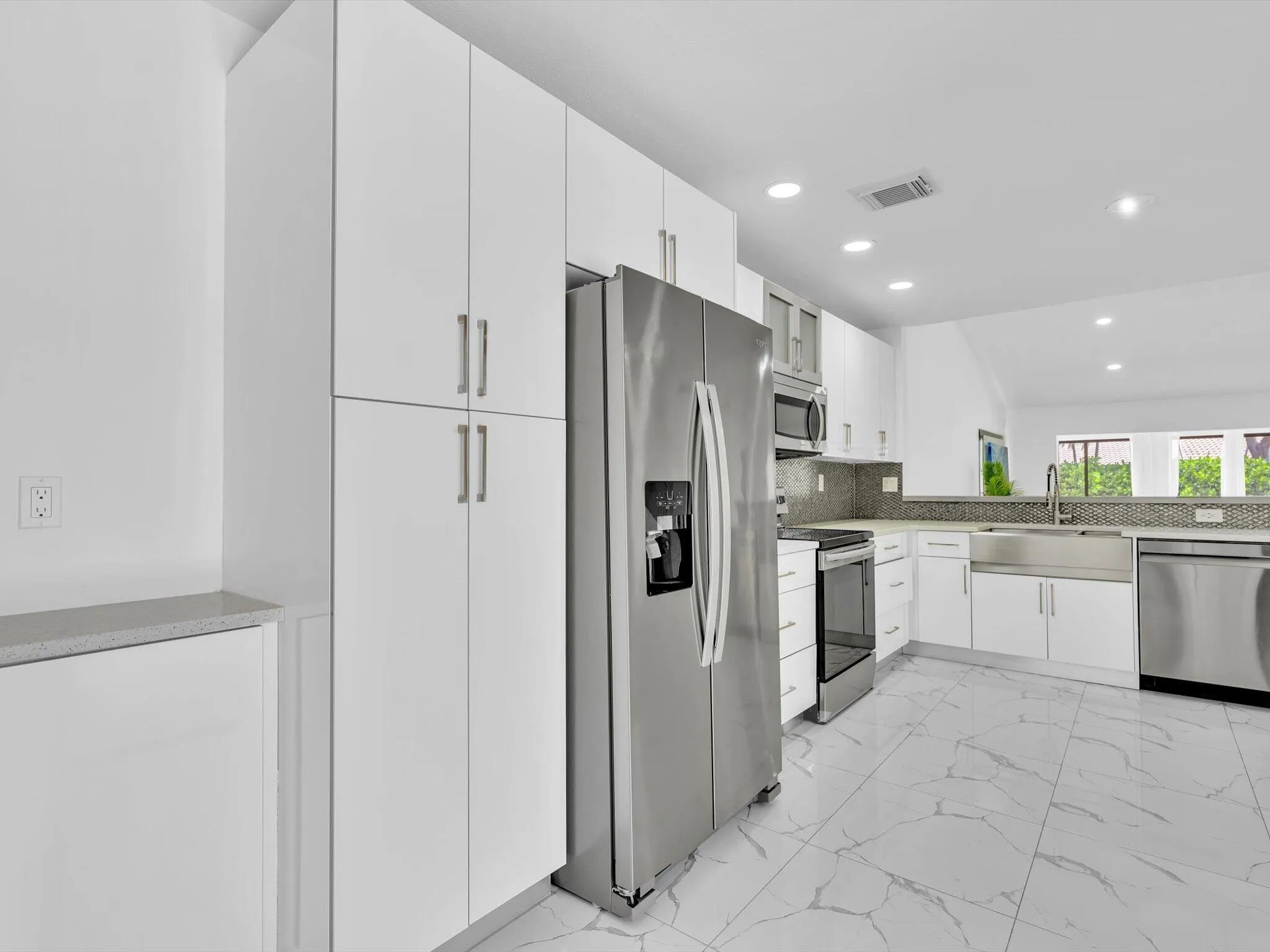 Modern kitchen featuring white cabinetry, stainless steel appliances, a large stainless steel sink, tile flooring, and recessed lighting