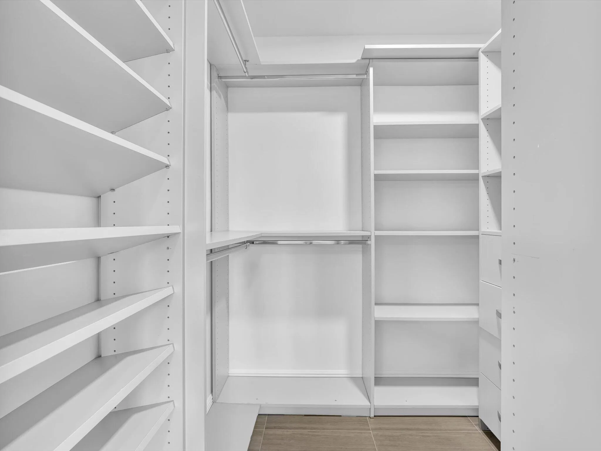 Custom closet system featuring multiple hanging rods, adjustable shelving, and integrated drawers