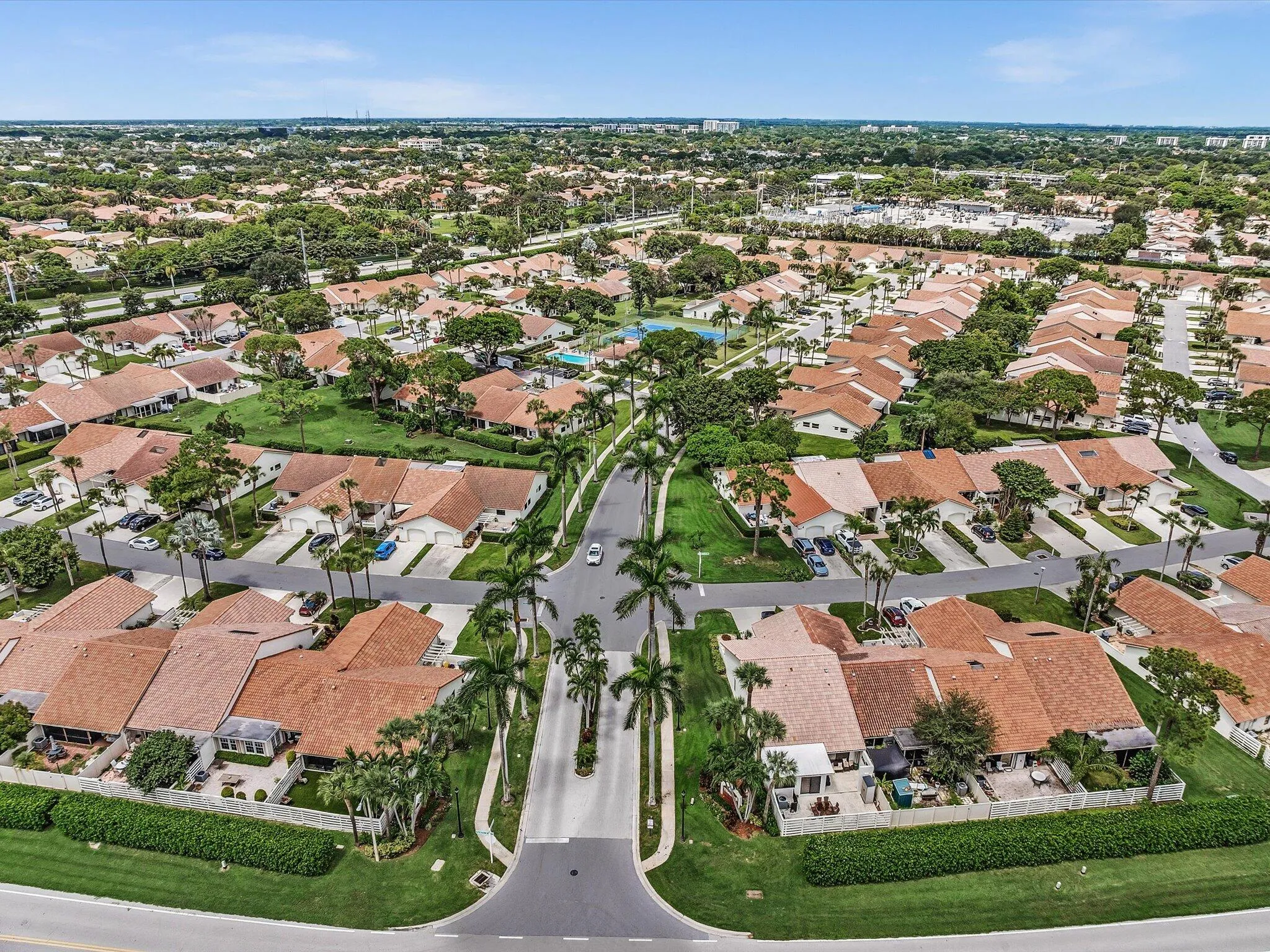 Residential community with uniform terracotta-style roofing, mature landscaping, and multiple street access points