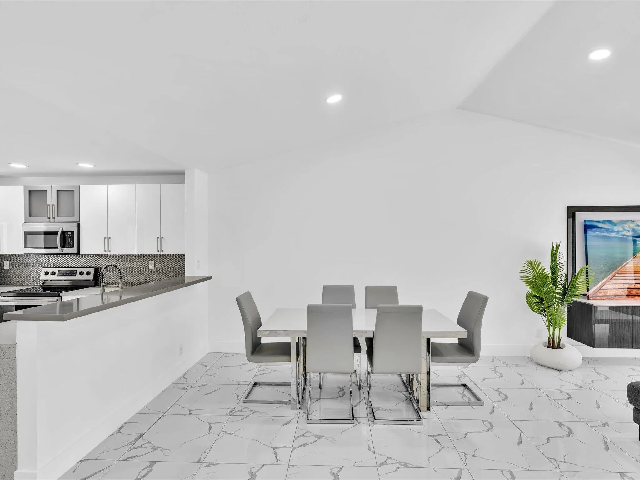 White kitchen cabinetry with stainless steel appliances, dark gray backsplash, and light gray countertops