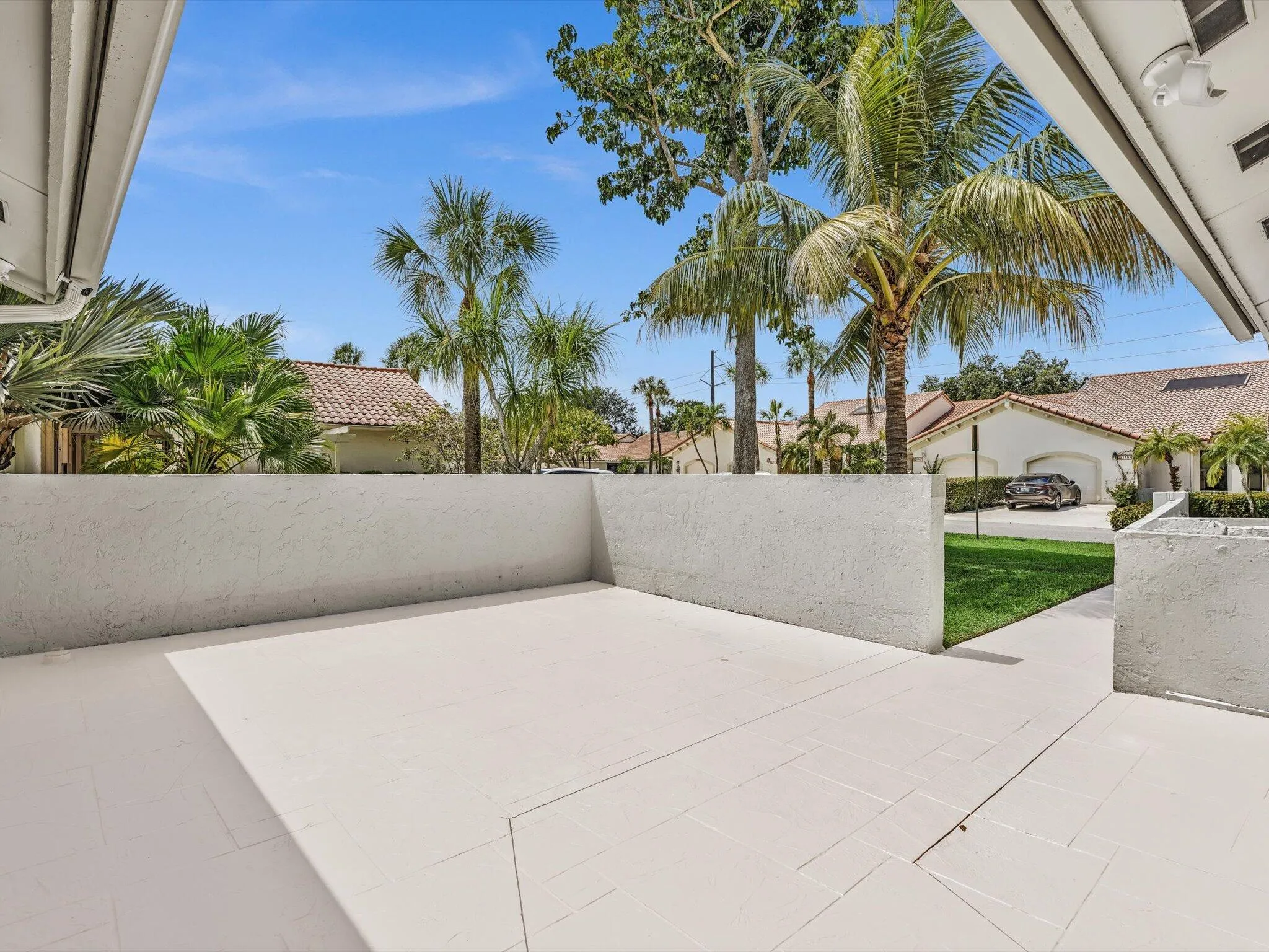 Private patio space with light-toned tile flooring and stucco walls