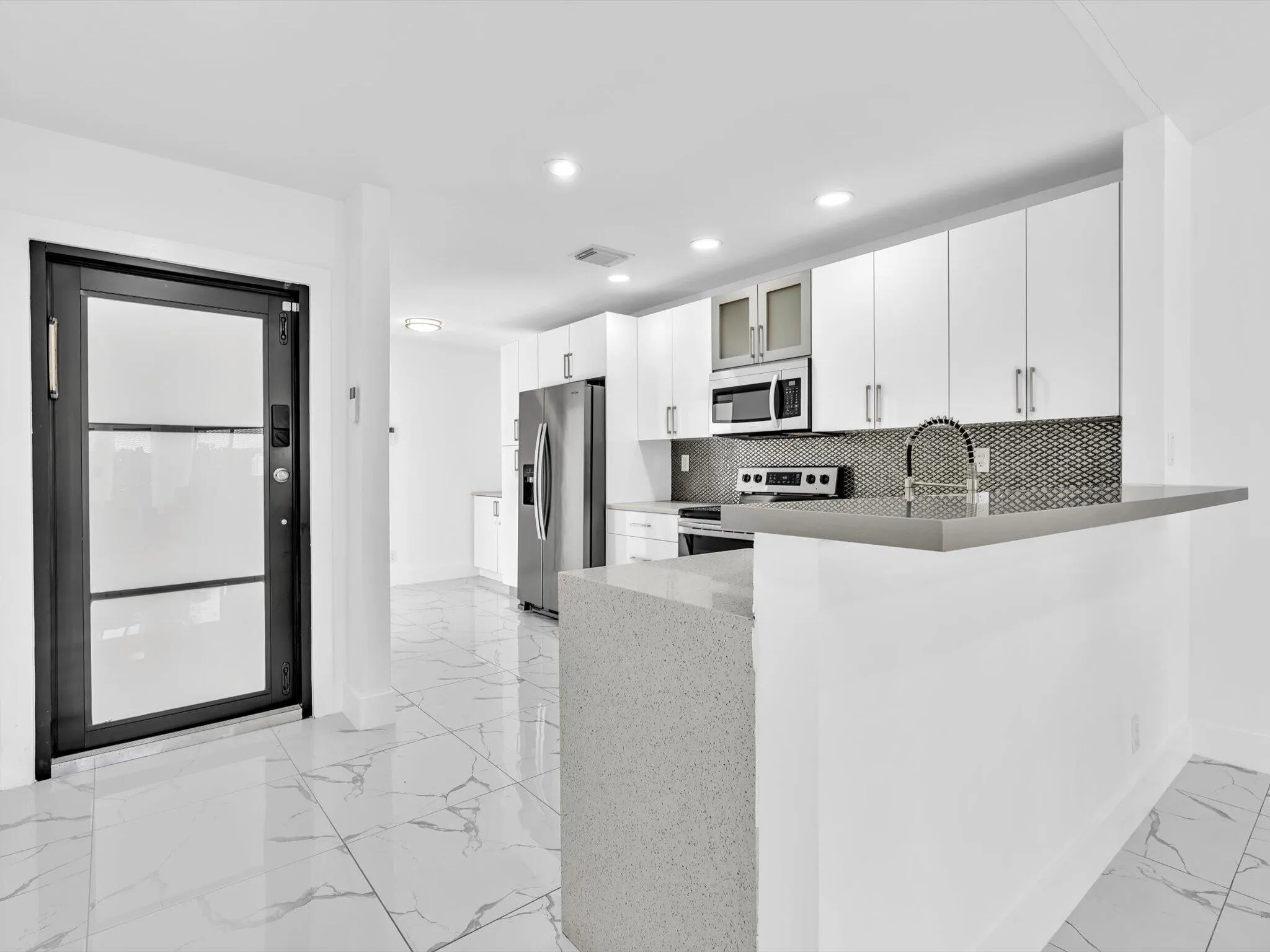 Gourmet kitchen with stainless steel appliances, white cabinetry, a tile backsplash, and an extended breakfast bar