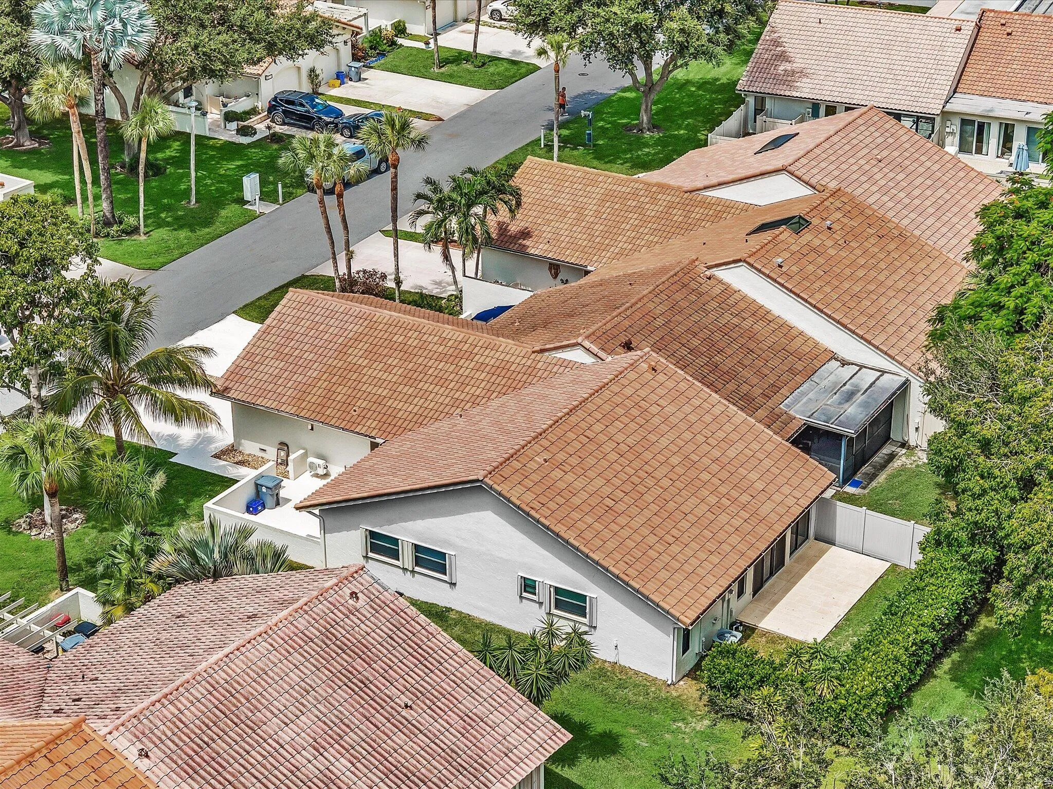 Terracotta tile roofs, mature palm trees, manicured landscaping, paved driveway, and private patio