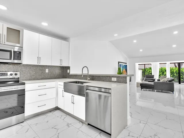 Modern kitchen featuring white cabinetry, stainless steel appliances, a farmhouse sink, and light-toned countertops