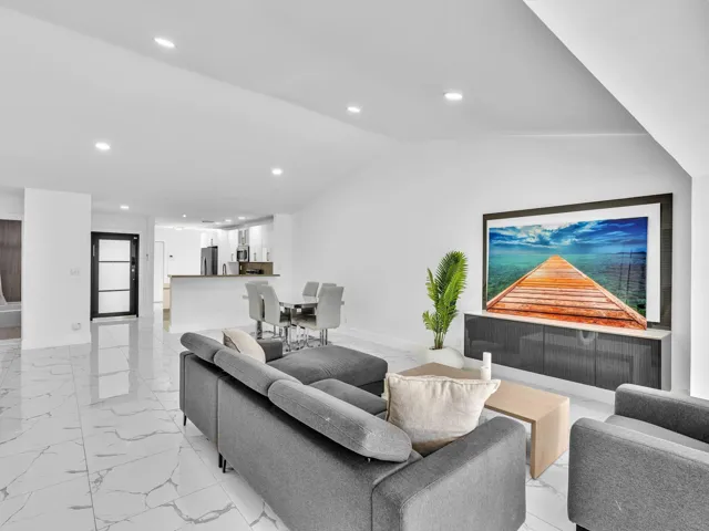 Open-concept living space featuring high vaulted ceilings, recessed lighting, large format tile flooring, and a contemporary media console