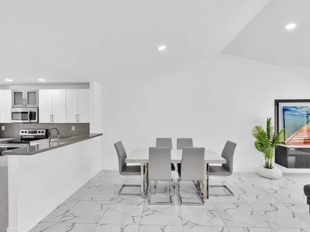 White kitchen cabinetry with stainless steel appliances, dark gray backsplash, and light gray countertops