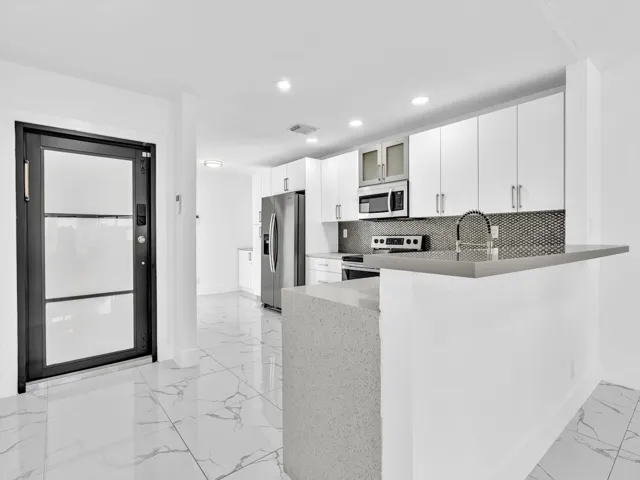 Gourmet kitchen with stainless steel appliances, white cabinetry, a tile backsplash, and an extended breakfast bar