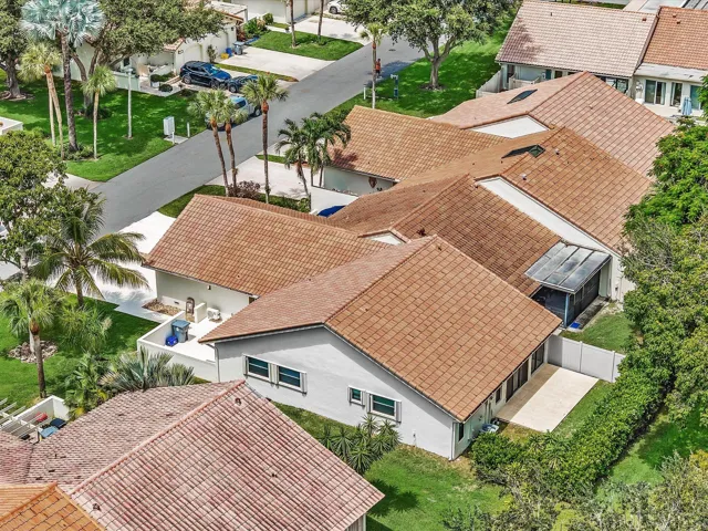 Terracotta tile roofs, mature palm trees, manicured landscaping, paved driveway, and private patio