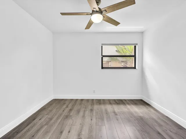 Recessed window with black framing, wood-finish flooring, white painted walls, and a ceiling fan with integrated lighting