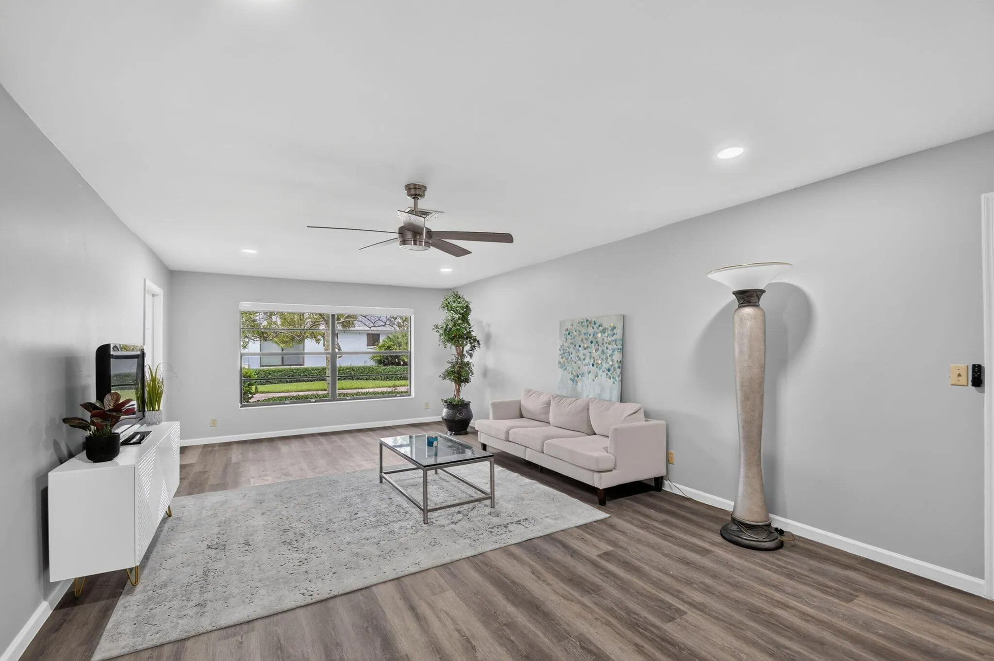 Recessed lighting, ceiling fan, expansive window, wood-finish flooring, and neutral wall tones