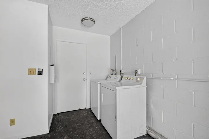 Laundry area with cinder block walls, overhead lighting, and a solid door
