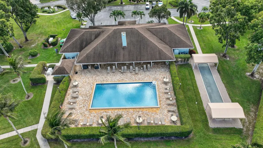 Community clubhouse featuring a rectangular swimming pool, paver deck, and a bocce ball court with covered ends