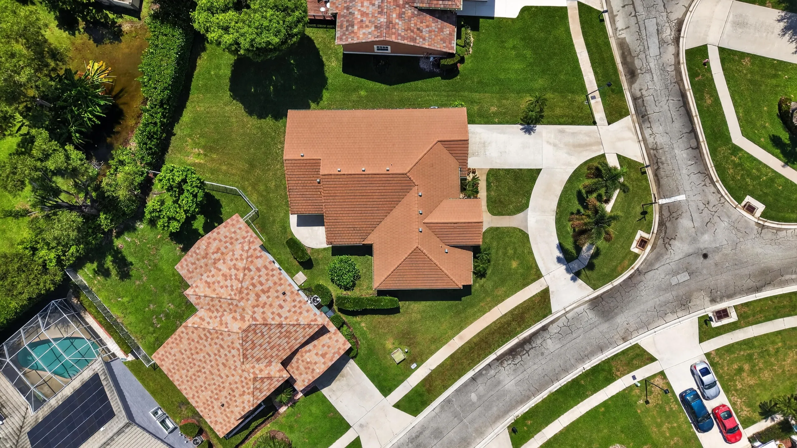 Tiled roof residence with an attached garage, paved driveway, and manicured landscaping