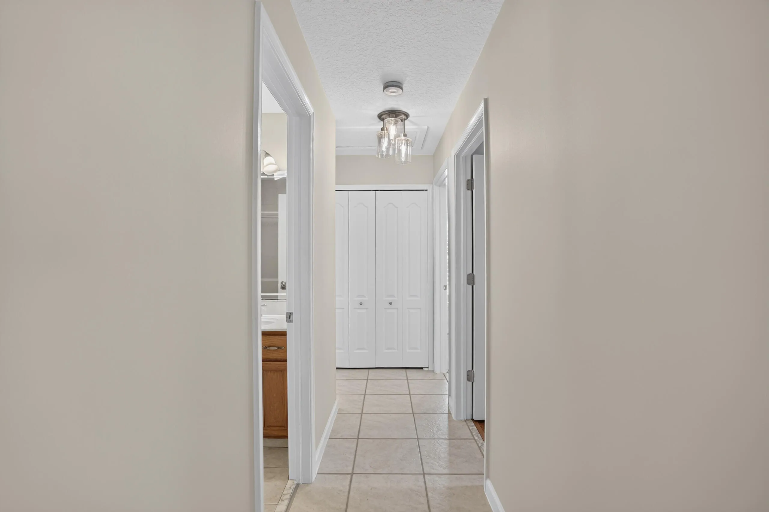 Hallway with tile flooring, recessed lighting, and a closet with bifold doors, split floor plan.