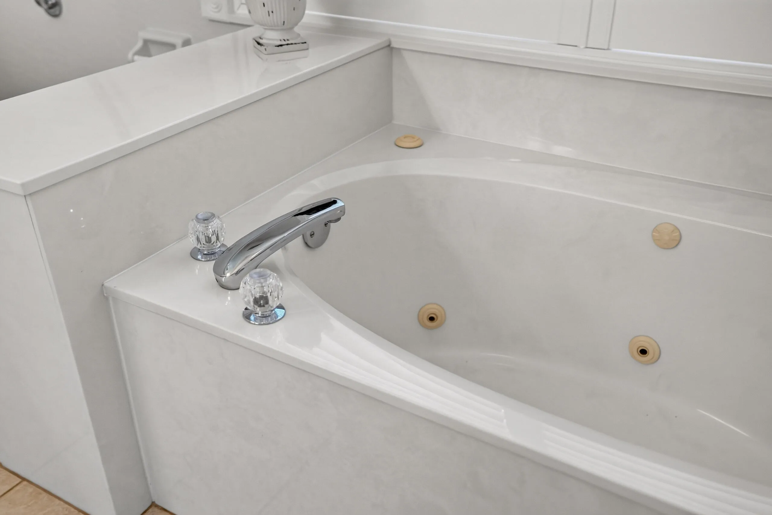 Built-in jetted tub with chrome fixtures and crystal-look handles
