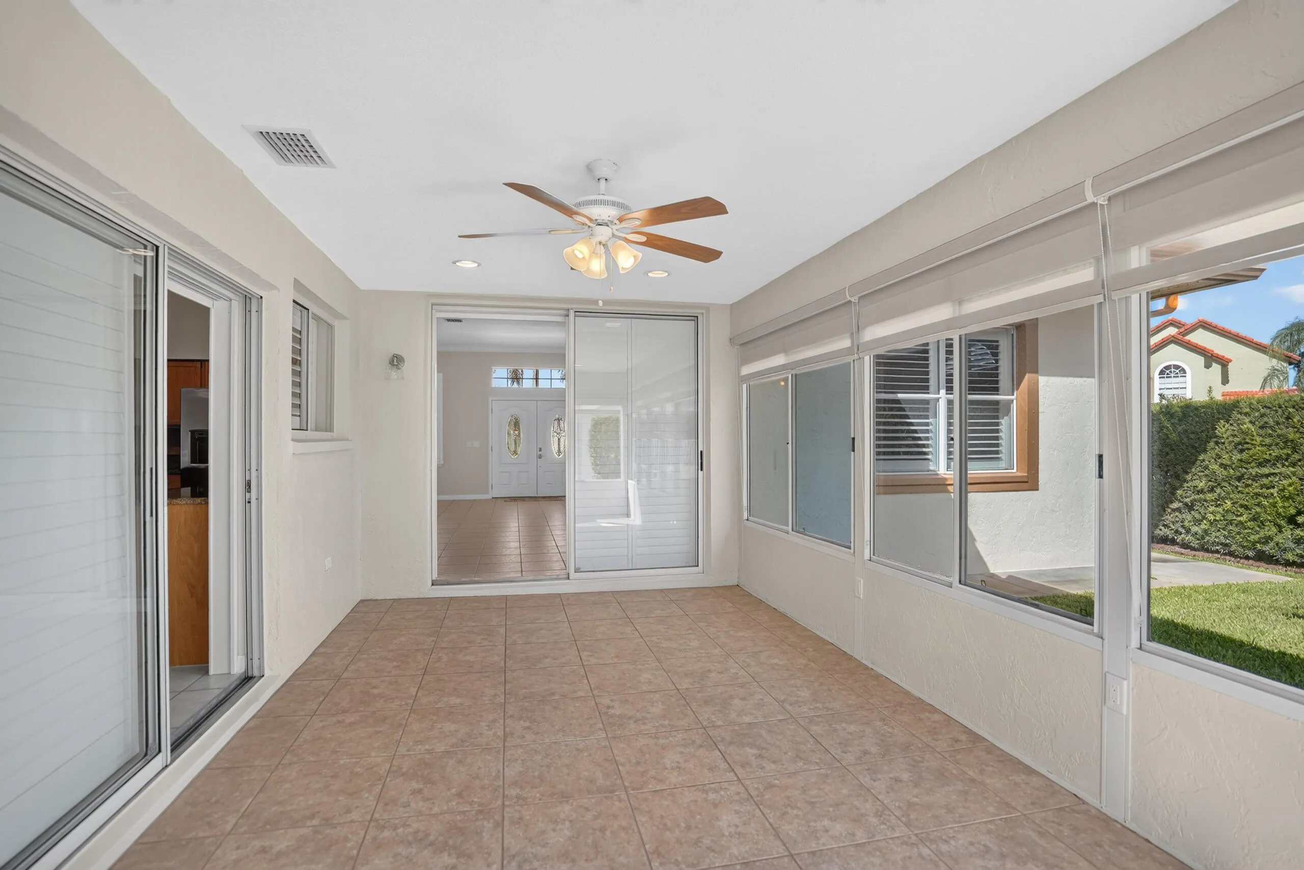 Enclosed patio featuring tile flooring, a ceiling fan, recessed lighting, and multiple sliding glass doors and zebra shades