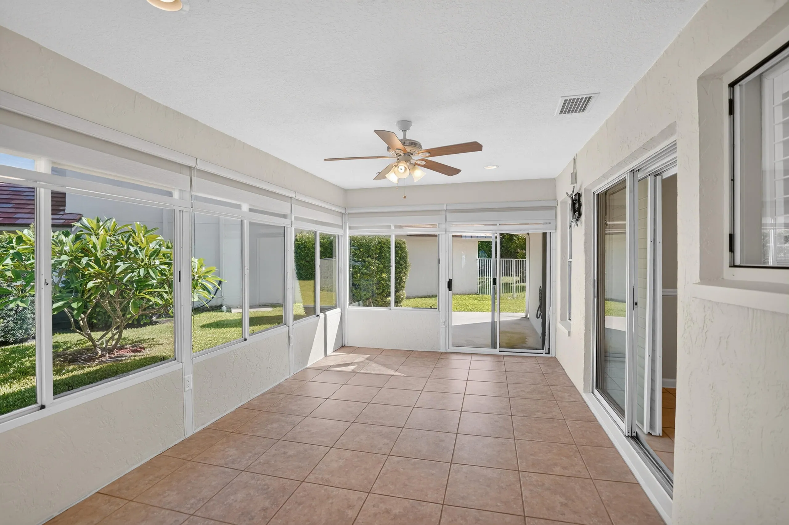 Enclosed patio featuring a ceiling fan, recessed lighting, tile flooring, and multiple sliding glass doors