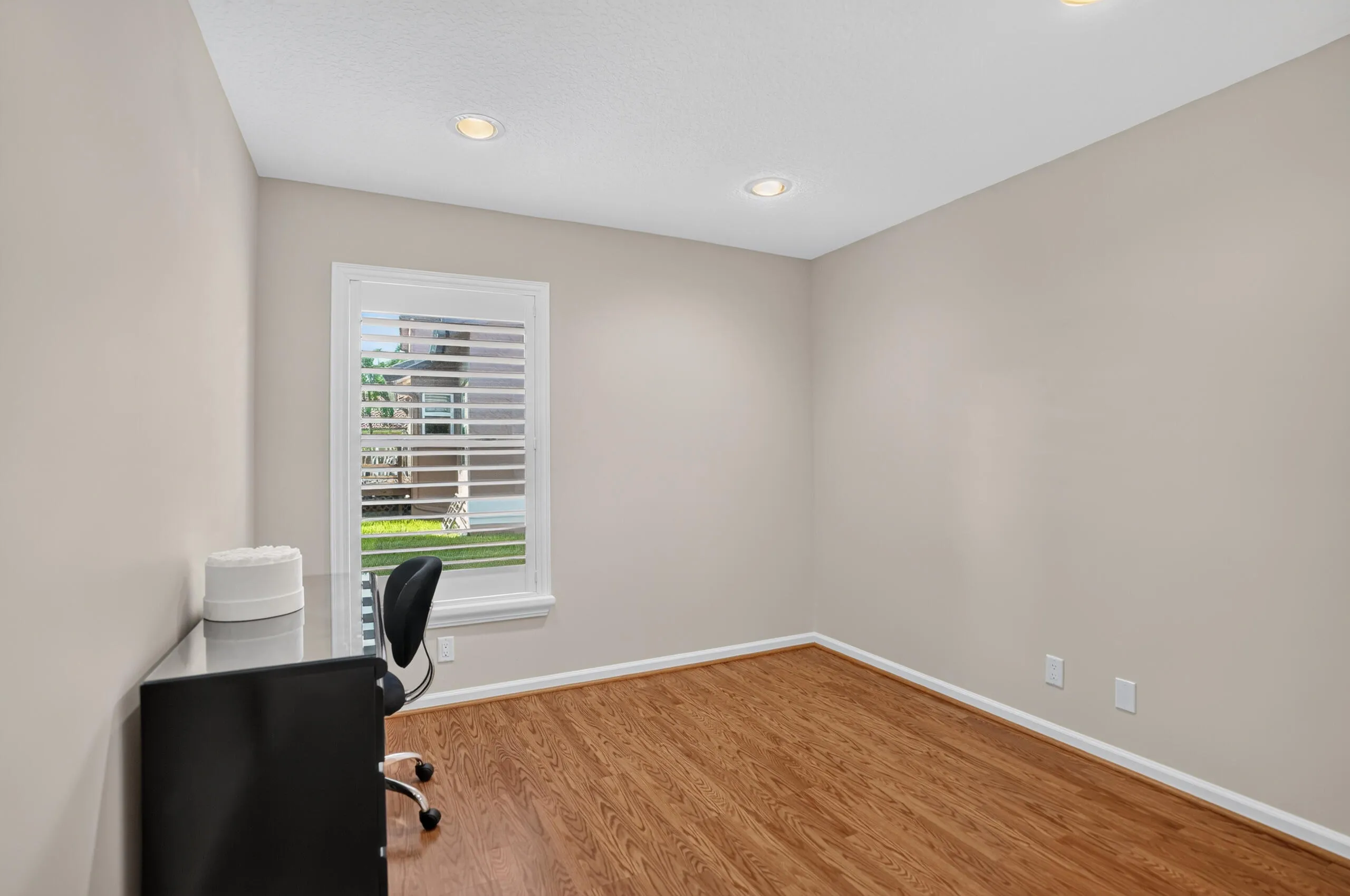 Recessed lighting, wood-finish flooring, neutral wall tones, white trim, and a window with plantation shutters