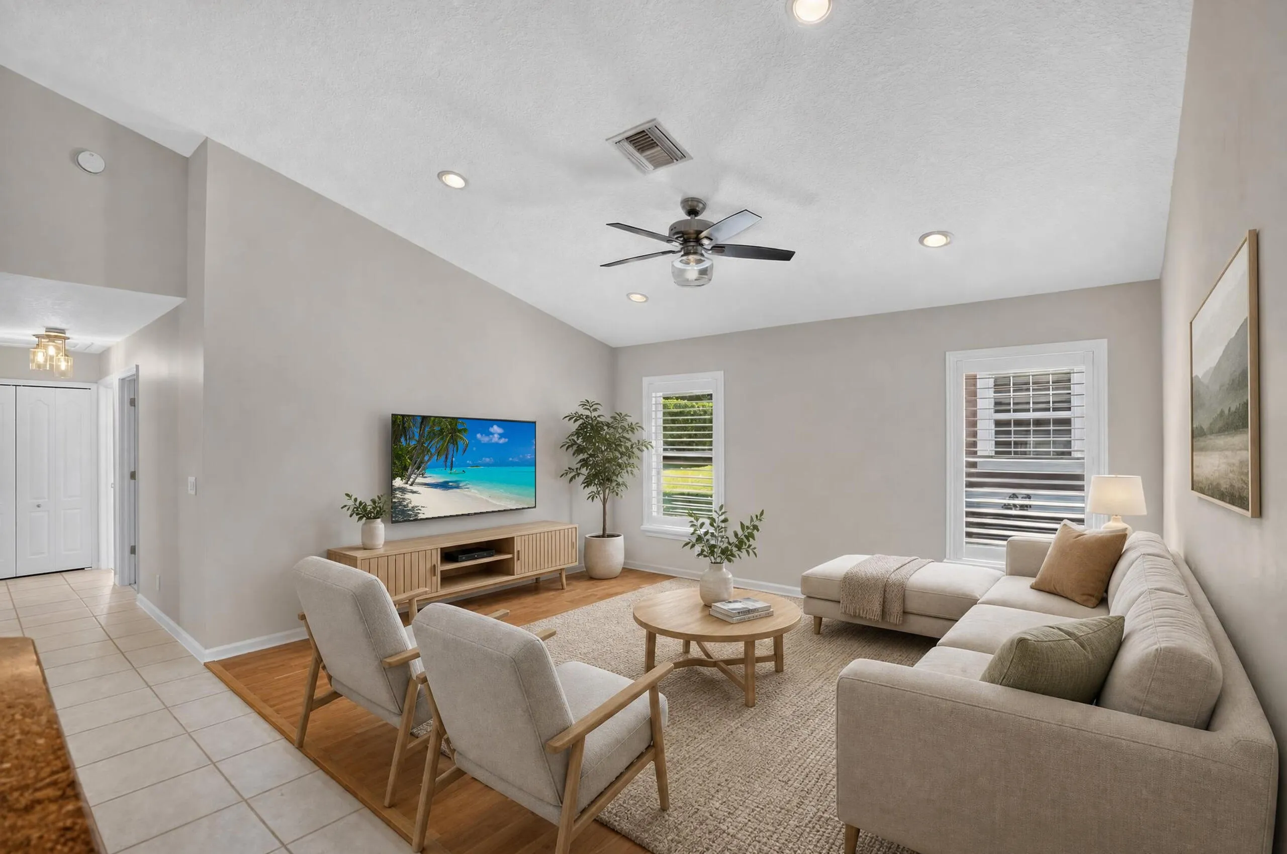 Vaulted ceiling with recessed lighting, ceiling fan, and window-mounted plantation shutters