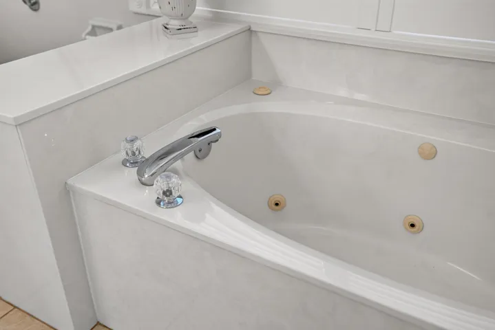Built-in jetted tub with chrome fixtures and crystal-look handles