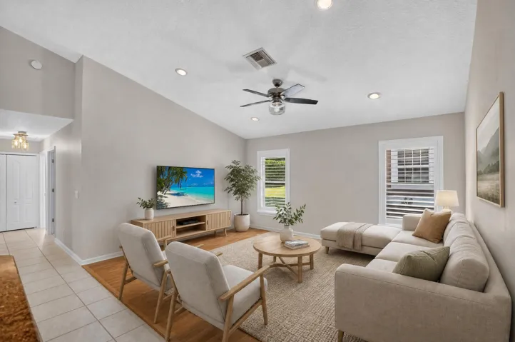 Vaulted ceiling with recessed lighting, ceiling fan, and window-mounted plantation shutters