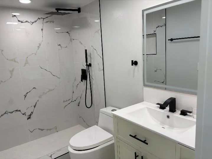 Shower with white and black veined tiling, matte black fixtures, and a rain shower head