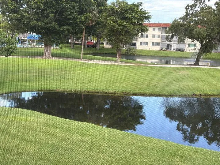Manicured lawn with mature trees and a tranquil lake view from patio