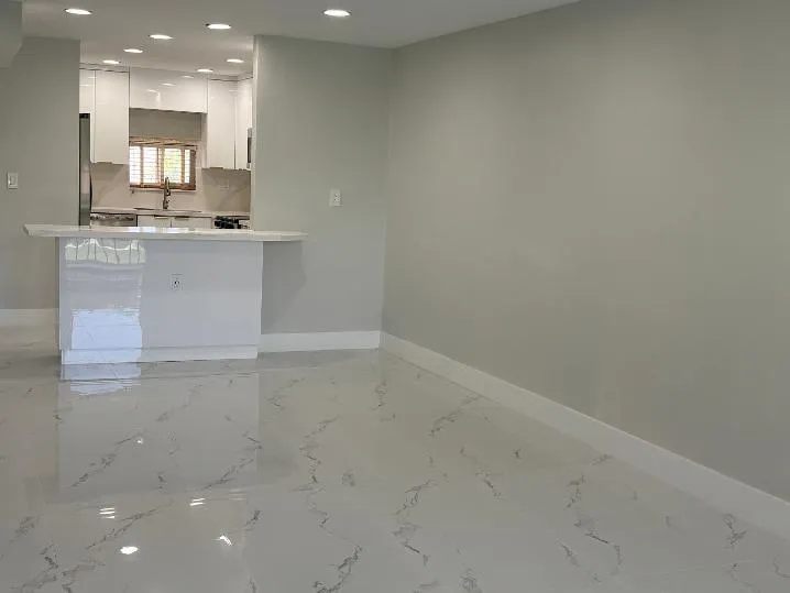 Glossy tile flooring, breakfast bar and recessed ceiling lighting, kitchen featuring white cabinetry and stainless steel appliances