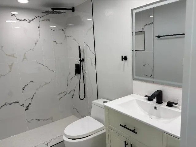 Shower with white and black veined tiling, matte black fixtures, and a rain shower head