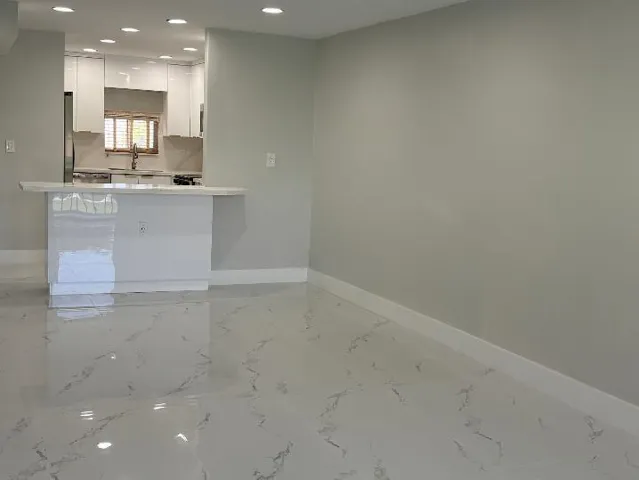Glossy tile flooring, breakfast bar and recessed ceiling lighting, kitchen featuring white cabinetry and stainless steel appliances