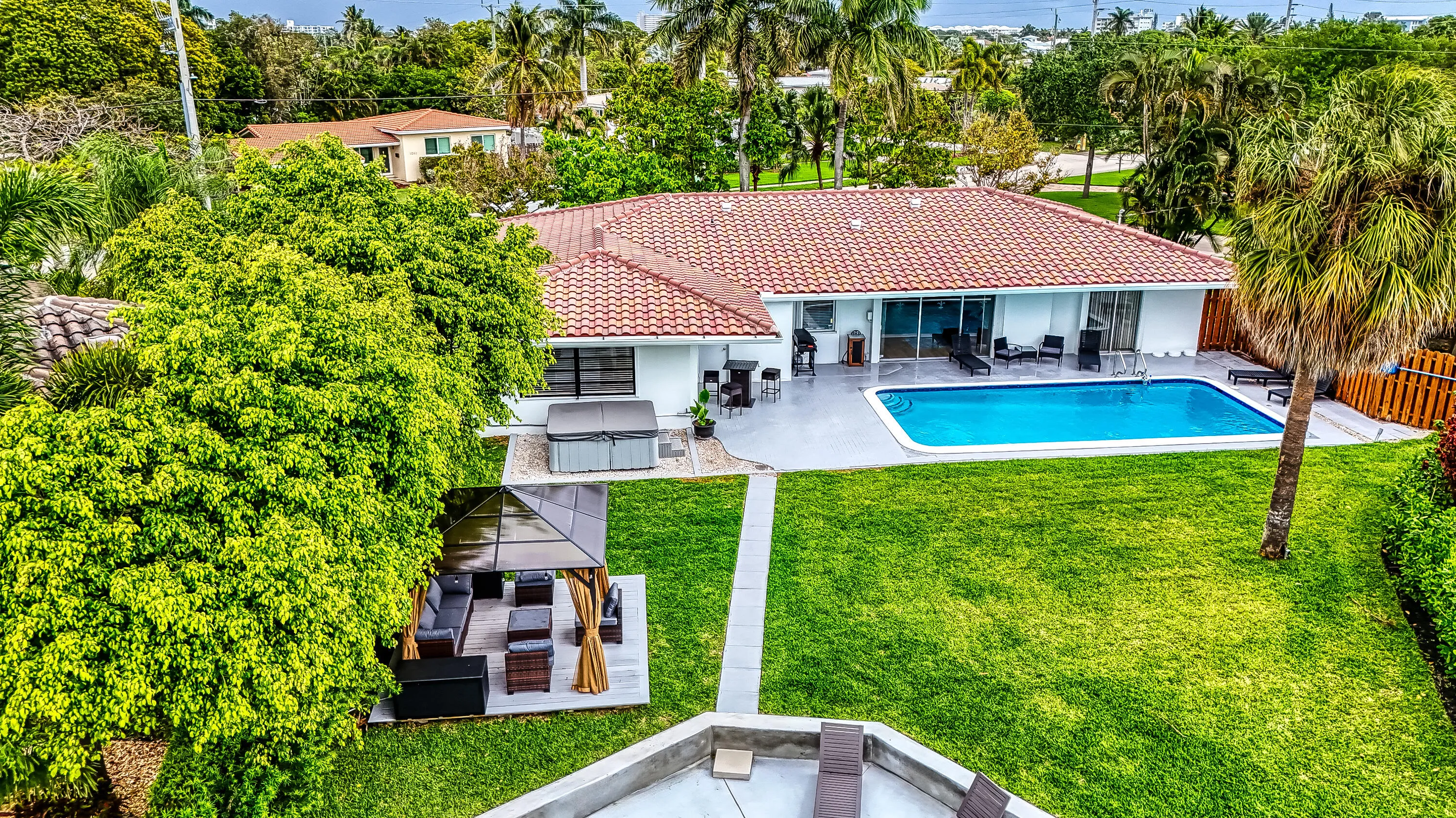 Expansive backyard featuring a rectangular swimming pool, concrete patio, and lush green lawn