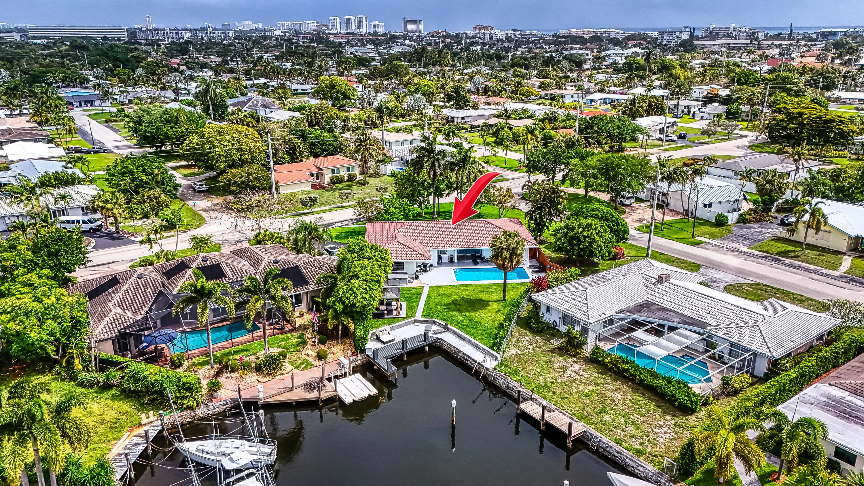 Waterfront property featuring a private dock, canal access, a manicured lawn, and an in-ground swimming pool