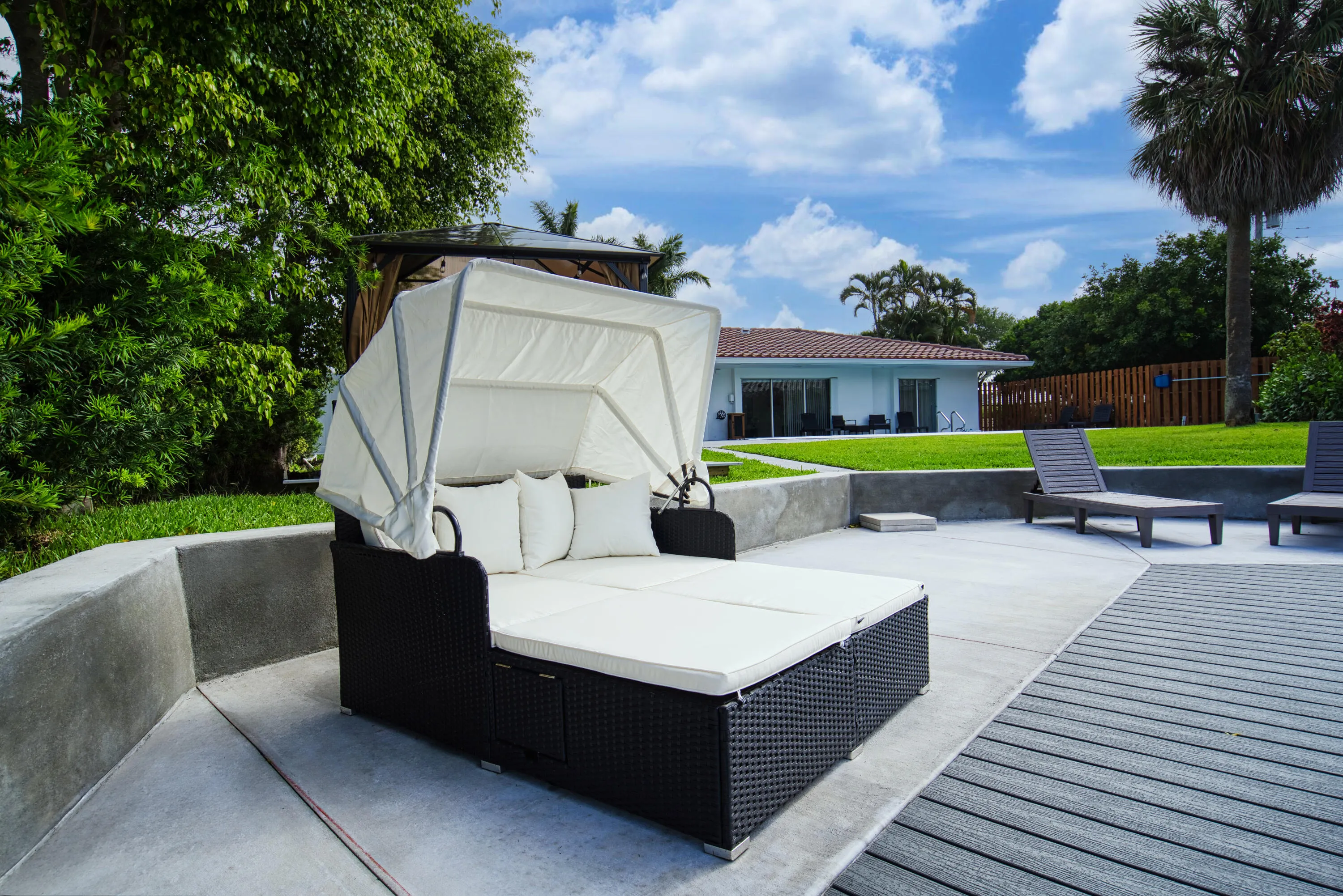 Outdoor entertaining area featuring concrete paving, composite decking, and a low concrete retaining wall