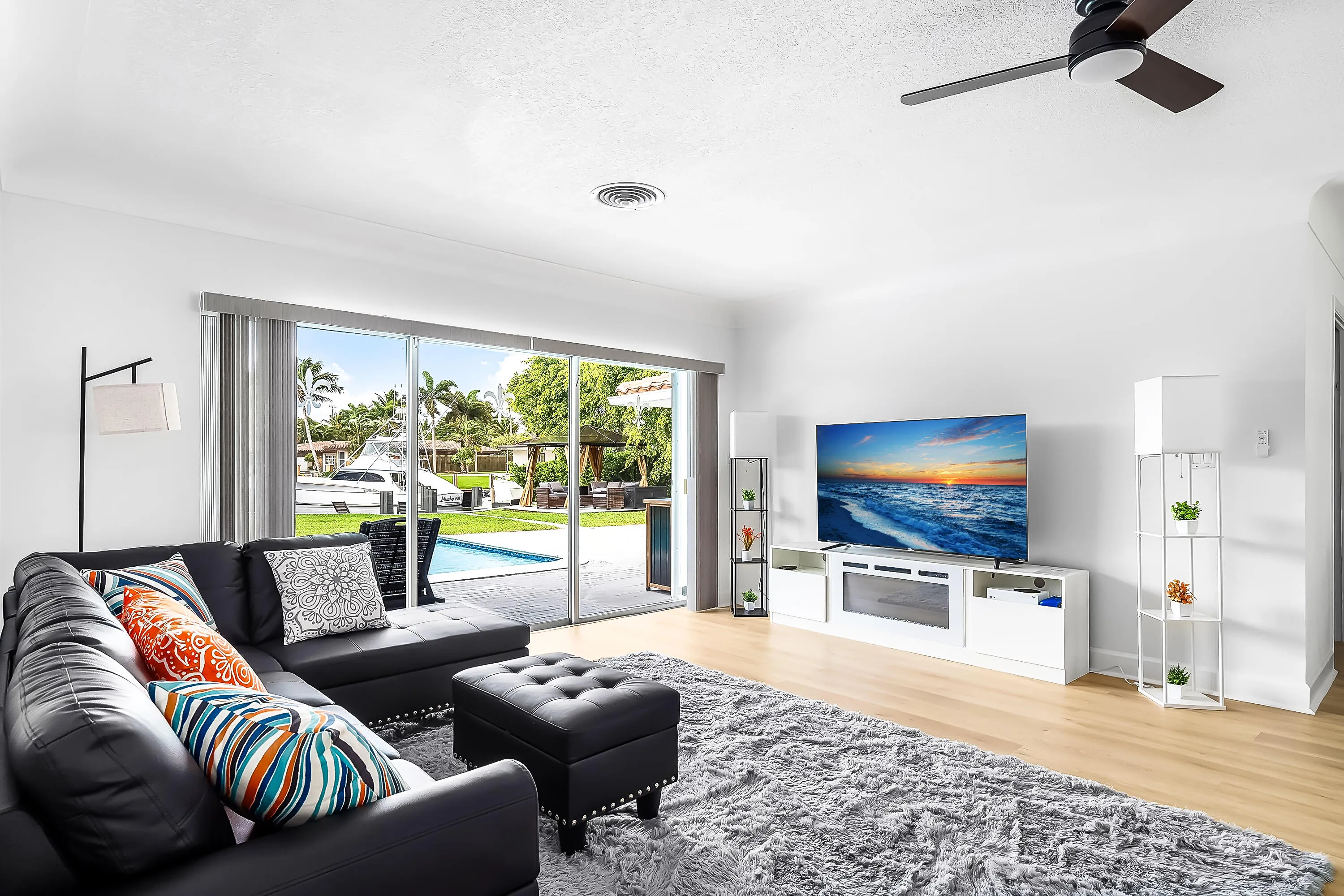 Living area featuring wood-finish flooring, a contemporary ceiling fan, and sliding glass doors opening to a private pool area