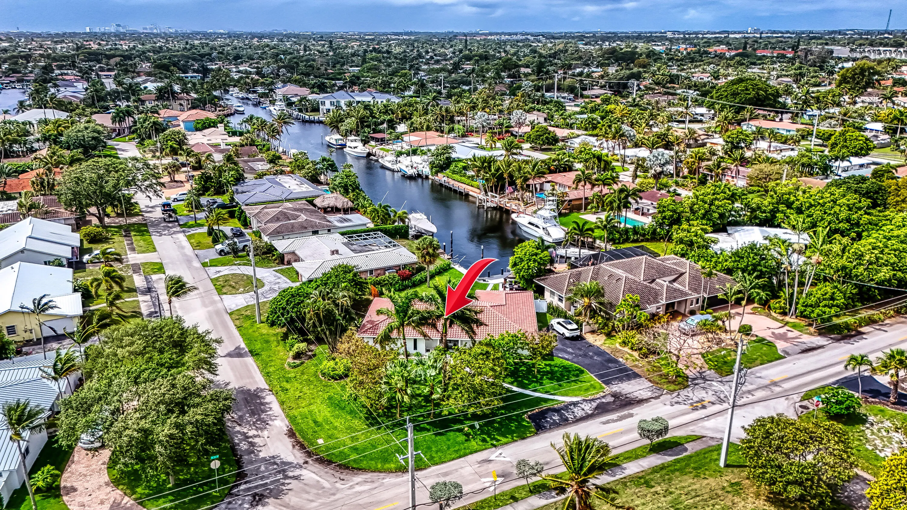 Waterfront property featuring extensive landscaping, a private driveway, and mature tropical foliage