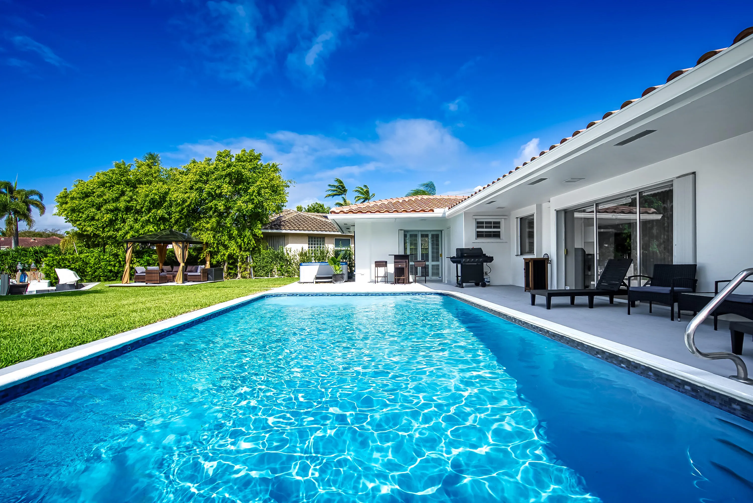 In-ground swimming pool with a tiled edge, surrounded by a concrete patio