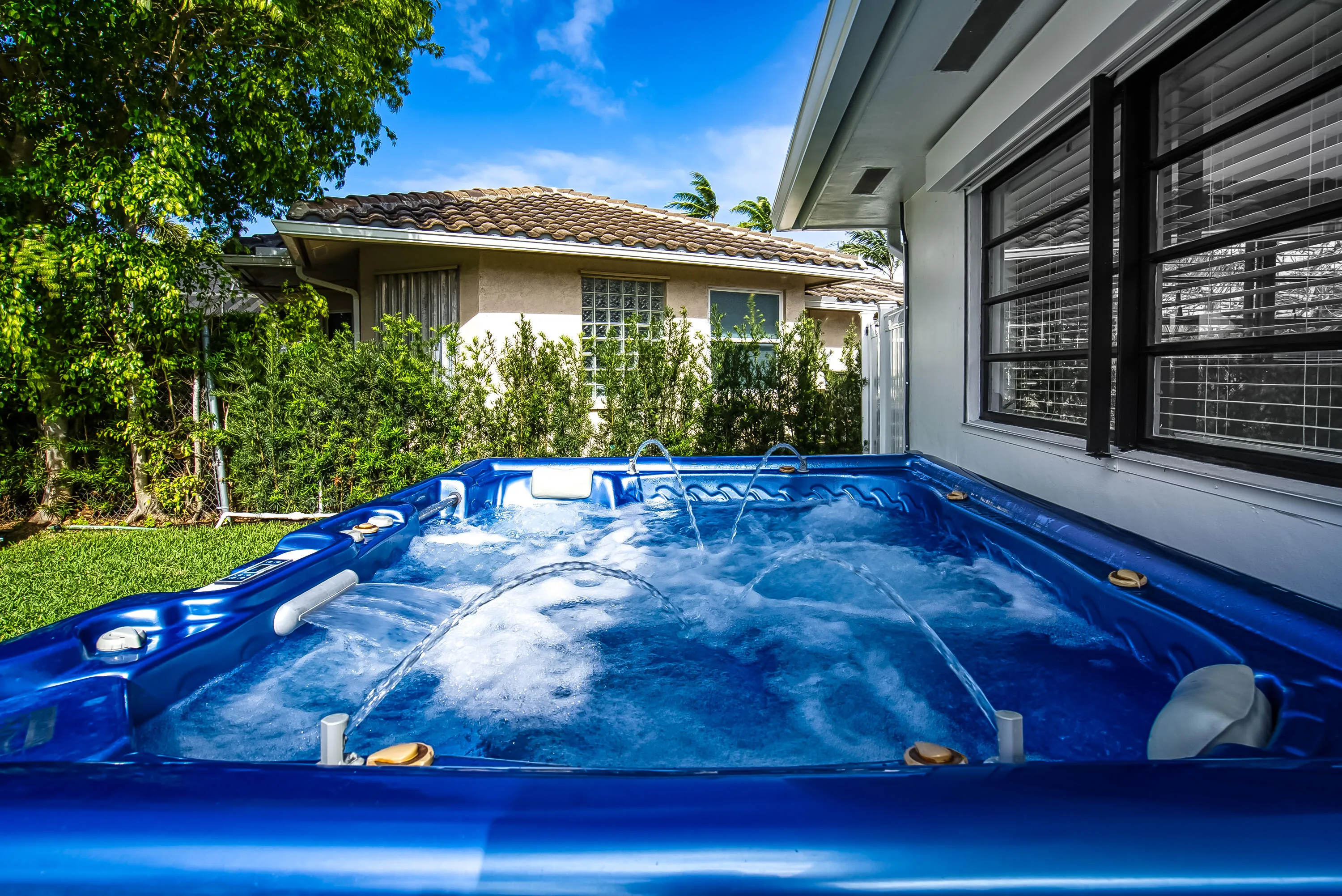 Invigorating blue spa with multiple jets, featuring a surrounding green lawn and mature landscaping