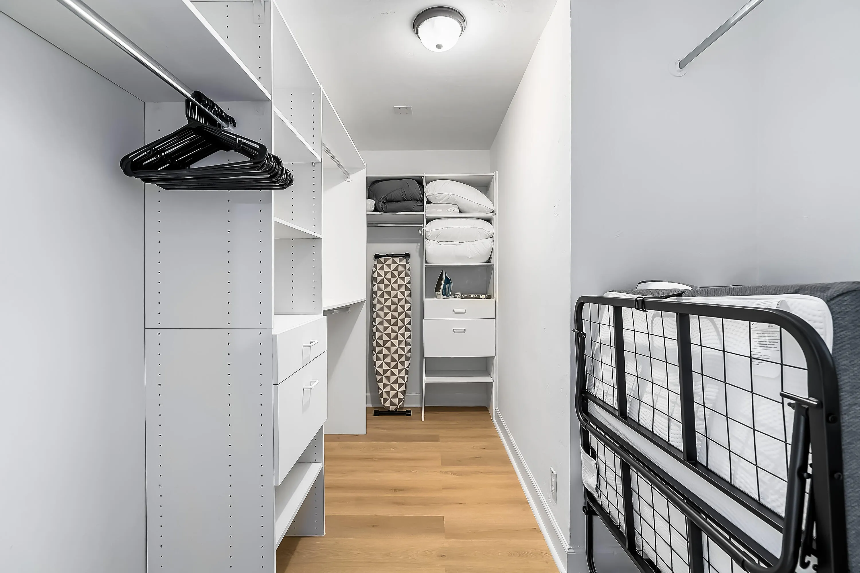 Custom closet system featuring white shelving, integrated drawers, and hanging rods