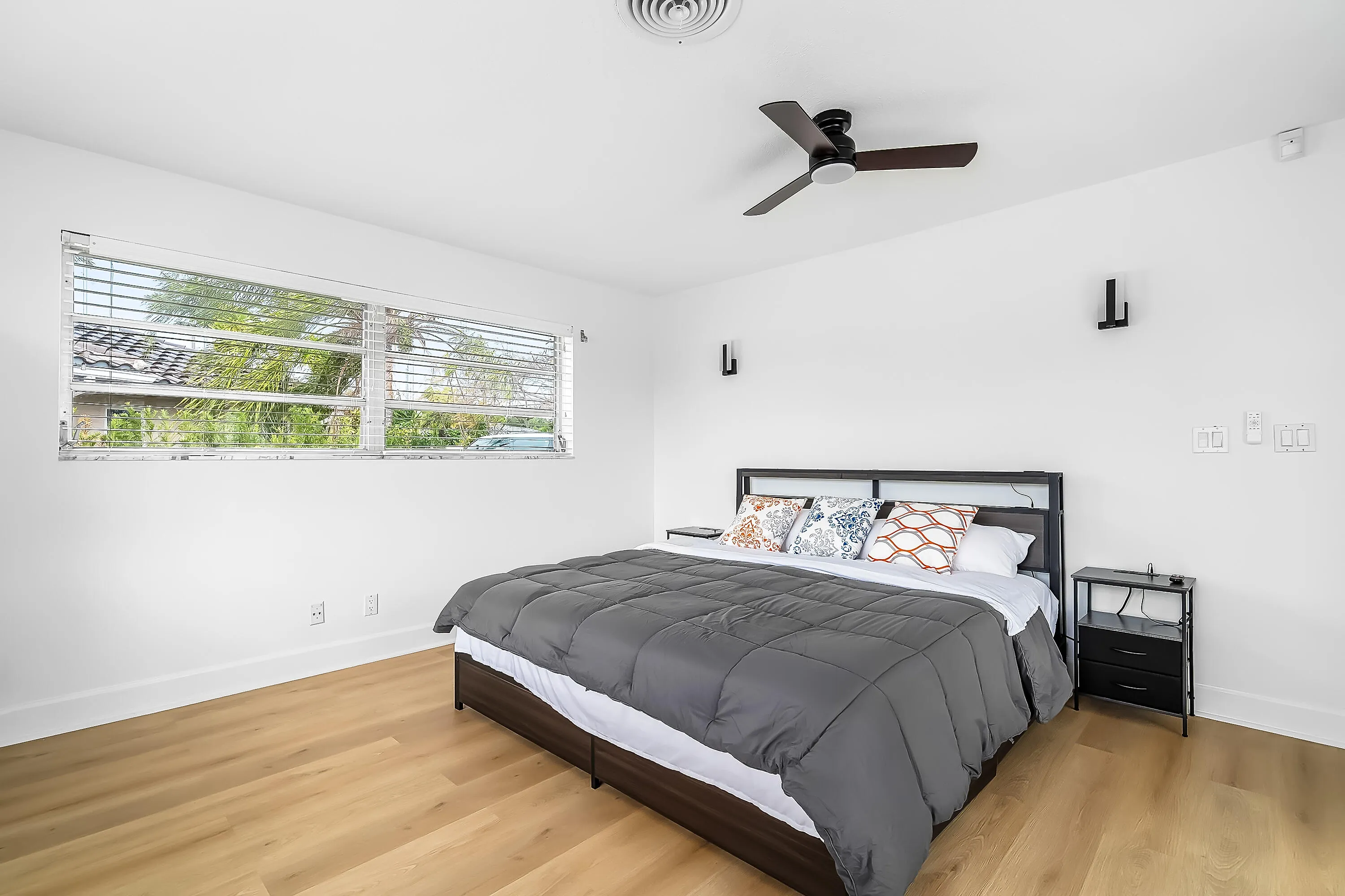 Bedroom featuring wood-finish flooring, a ceiling fan, and two wall-mounted light fixtures