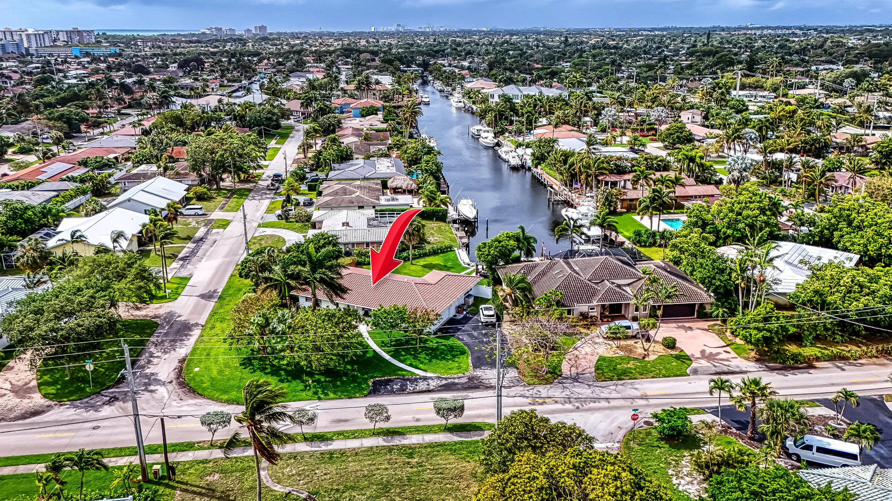 Waterfront property featuring a private boat dock, lush landscaping, and mature palm trees