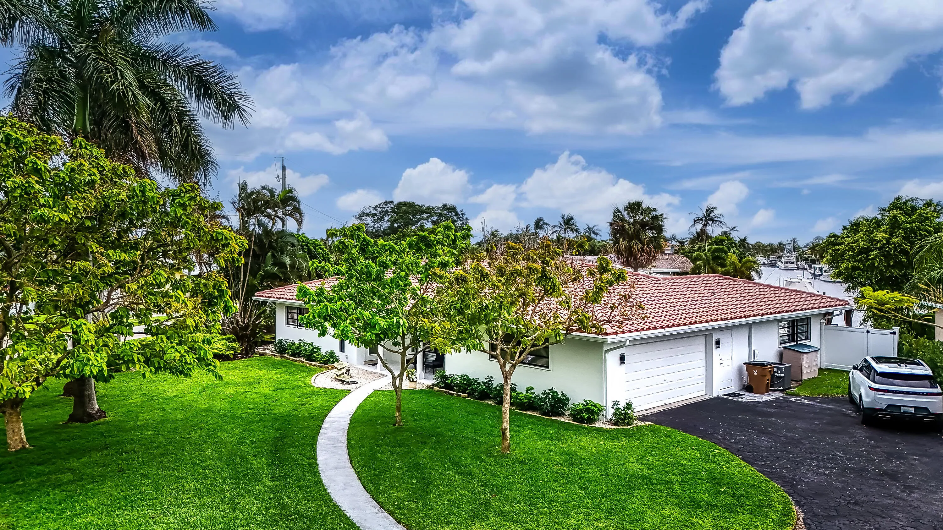 Exterior featuring a terracotta tile roof, white garage door, and a curved paved walkway