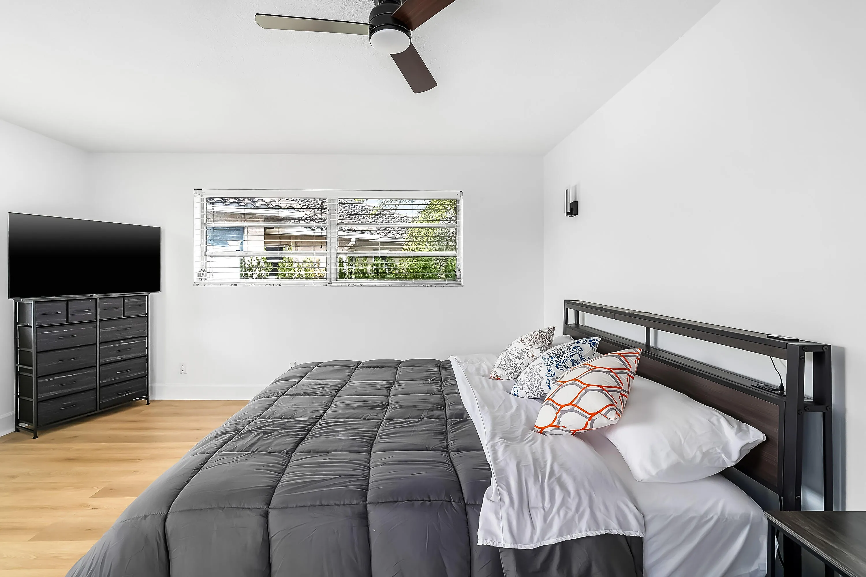 Interior room featuring wood-finish flooring, a ceiling fan with integrated lighting, and a horizontal window with blinds