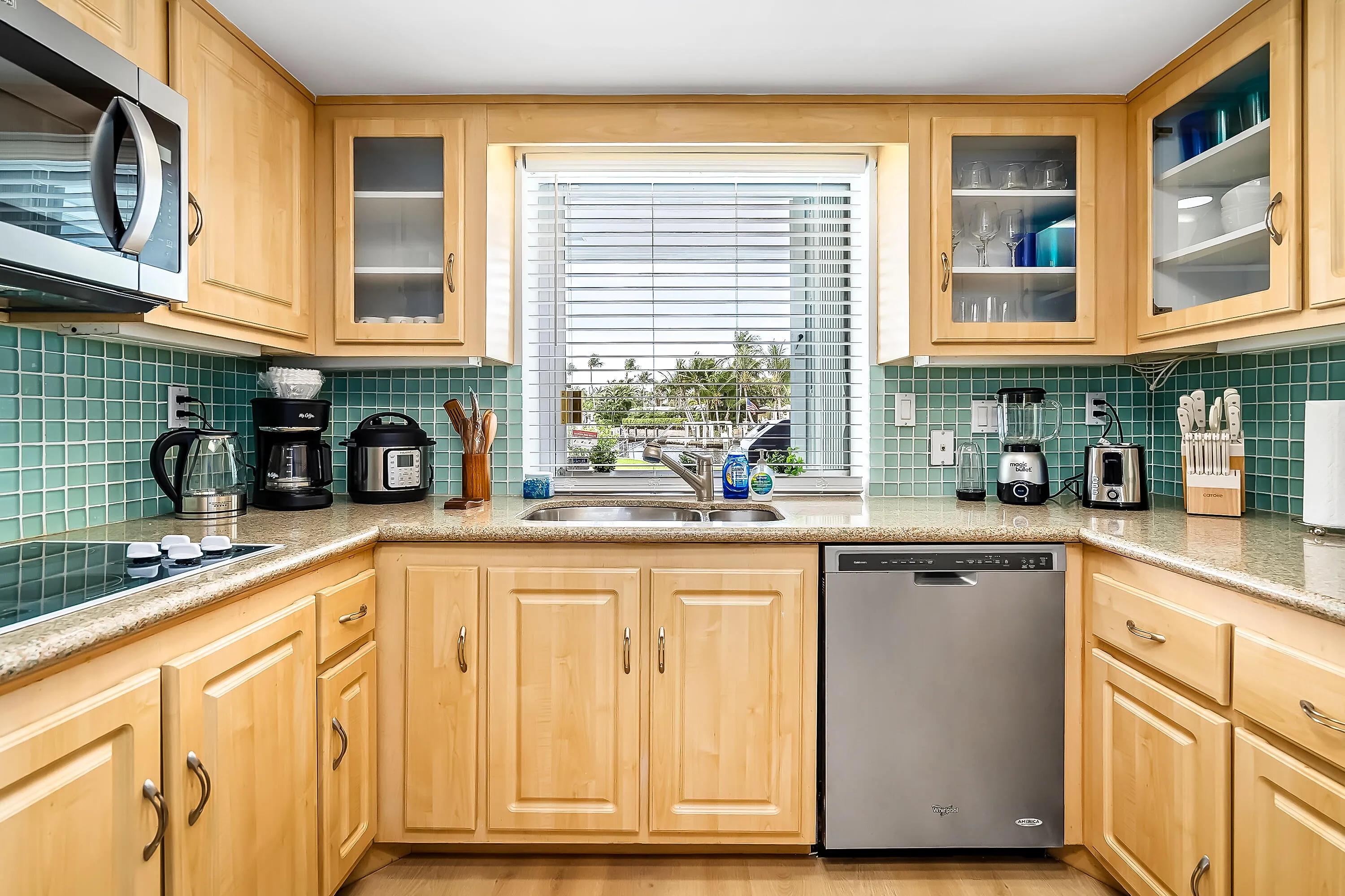 Kitchen featuring light wood cabinetry, a tiled backsplash, and stone-finish countertops