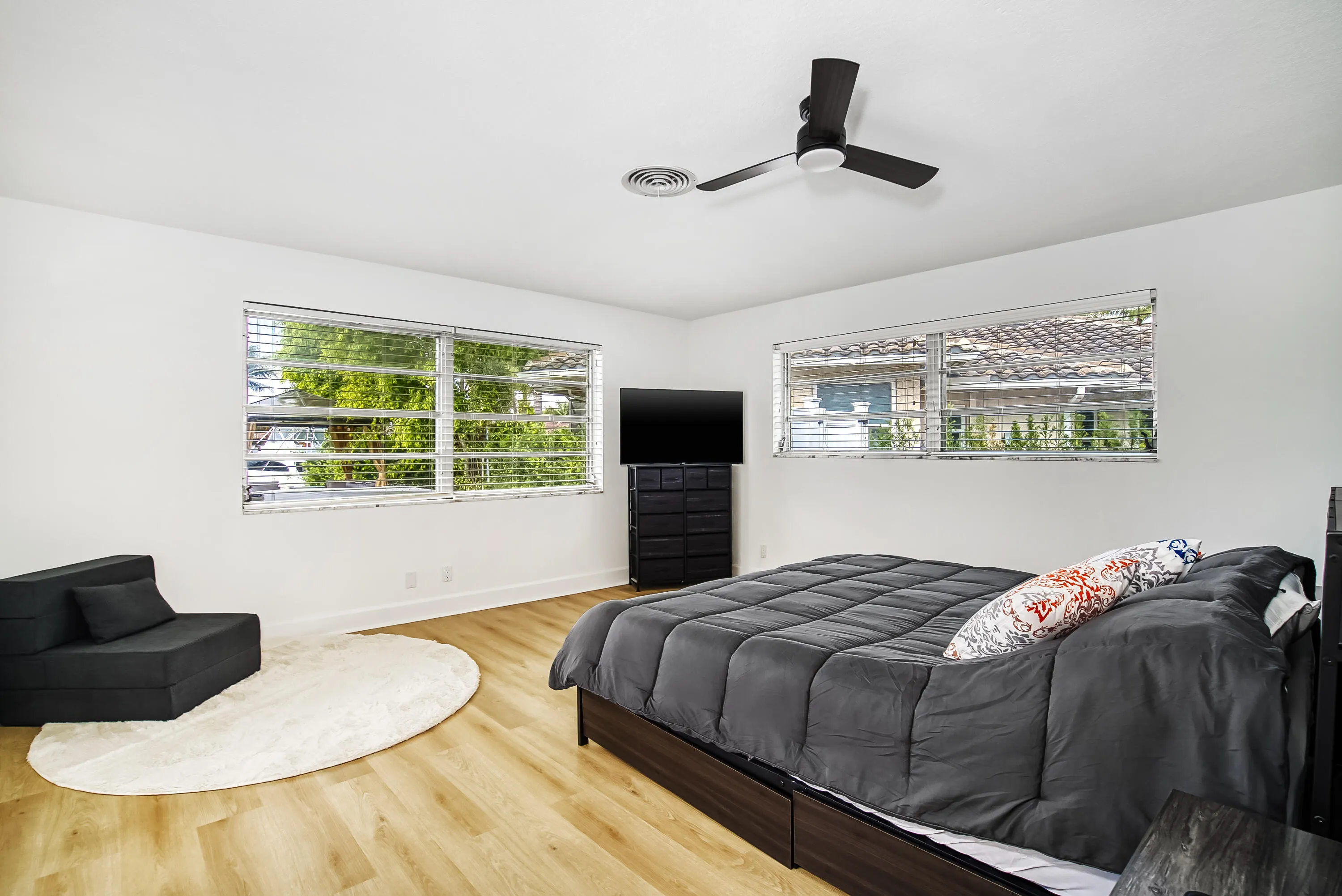 Spacious room featuring light wood-finish flooring, white walls, and a contemporary ceiling fan