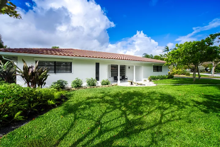 Single-story home featuring a terracotta tile roof, white stucco exterior, and black-framed windows