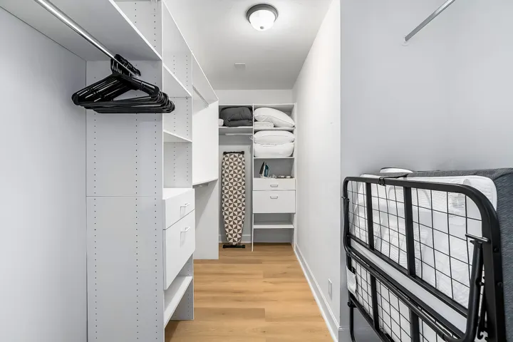 Custom closet system featuring white shelving, integrated drawers, and hanging rods