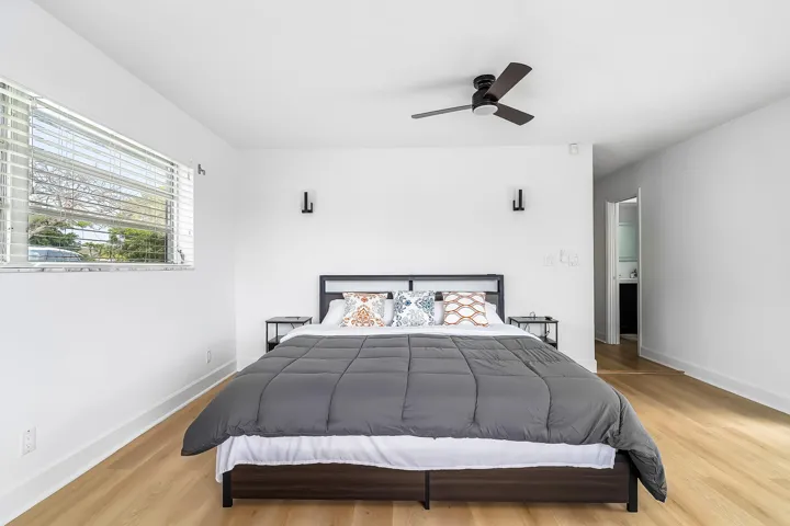 Bedroom featuring light wood-finish flooring, white walls, and a window with horizontal blinds